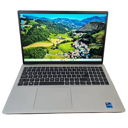 An open silver laptop with a black keyboard and screen, showing a mountain landscape wallpaper. The laptop is placed on a brown cardboard box on a gray carpet against a white wall.