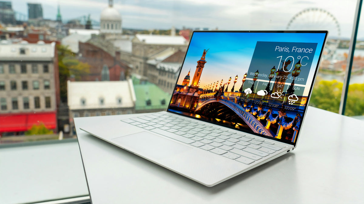 Laptop on a desk with a cityscape view outside the window